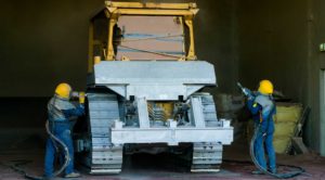 Men sandblast bulldozer